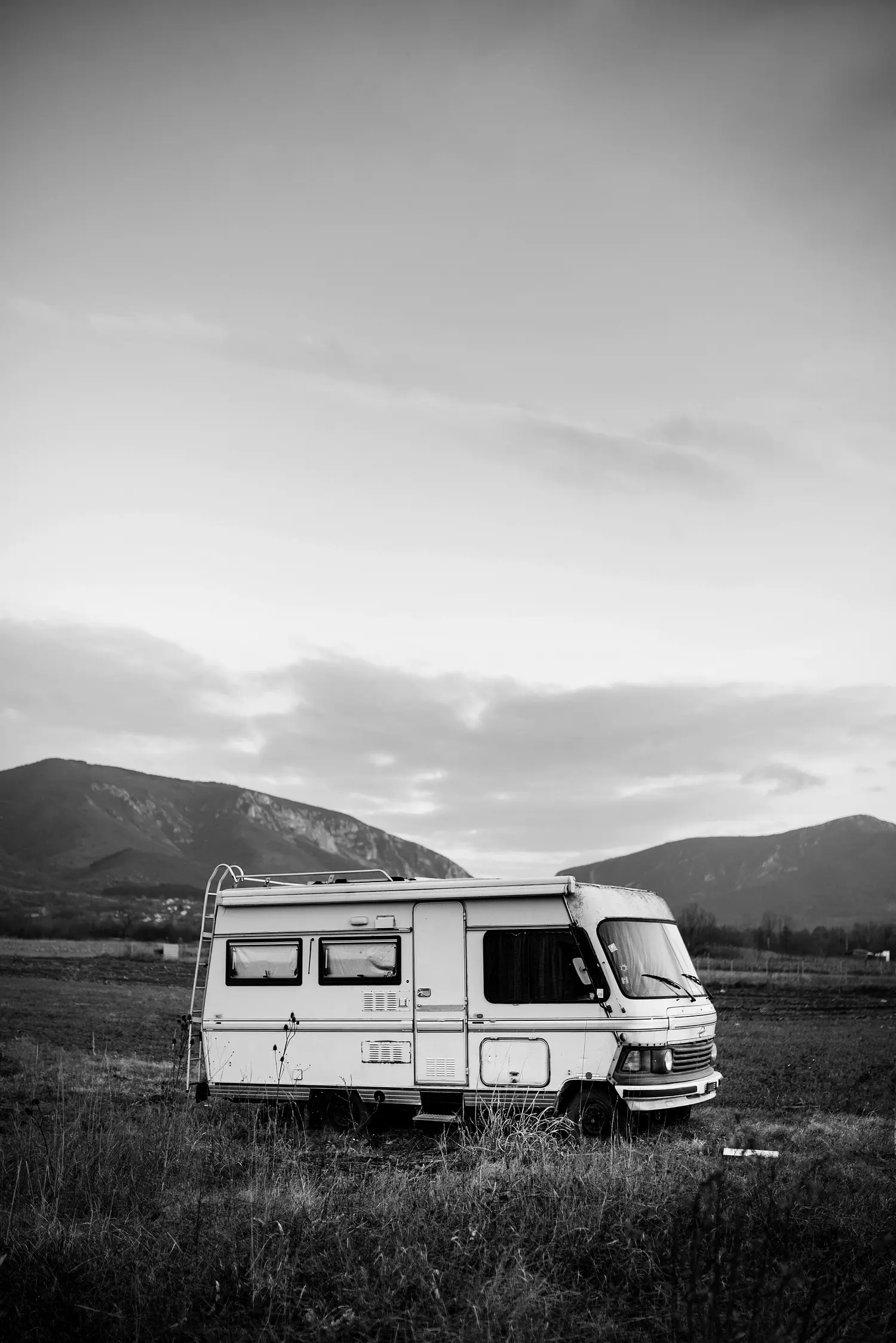 Un camper da solo in un prato al tramonto